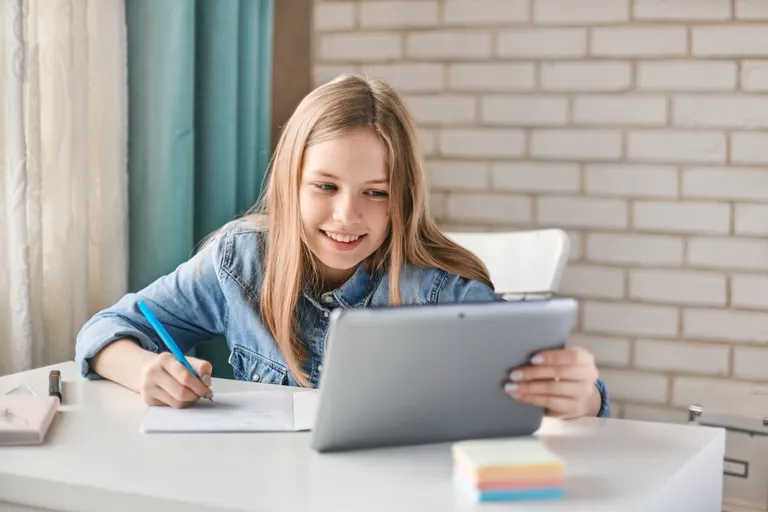 Tablet ve defterle ders çalışan öğrenci